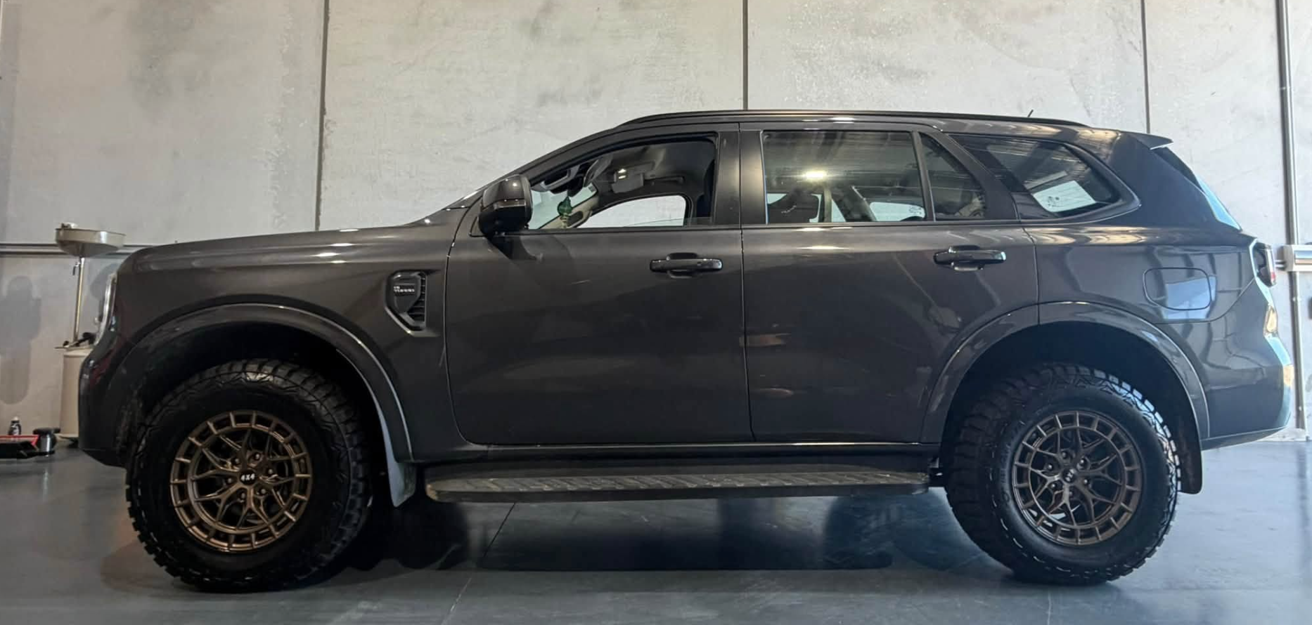 Grey Ford Everest four wheel drive on bronze alloy wheels and all-terrain tyres in the workshop at Australia's Most Wanted Wheels and Tyres Bathurst in Kelso