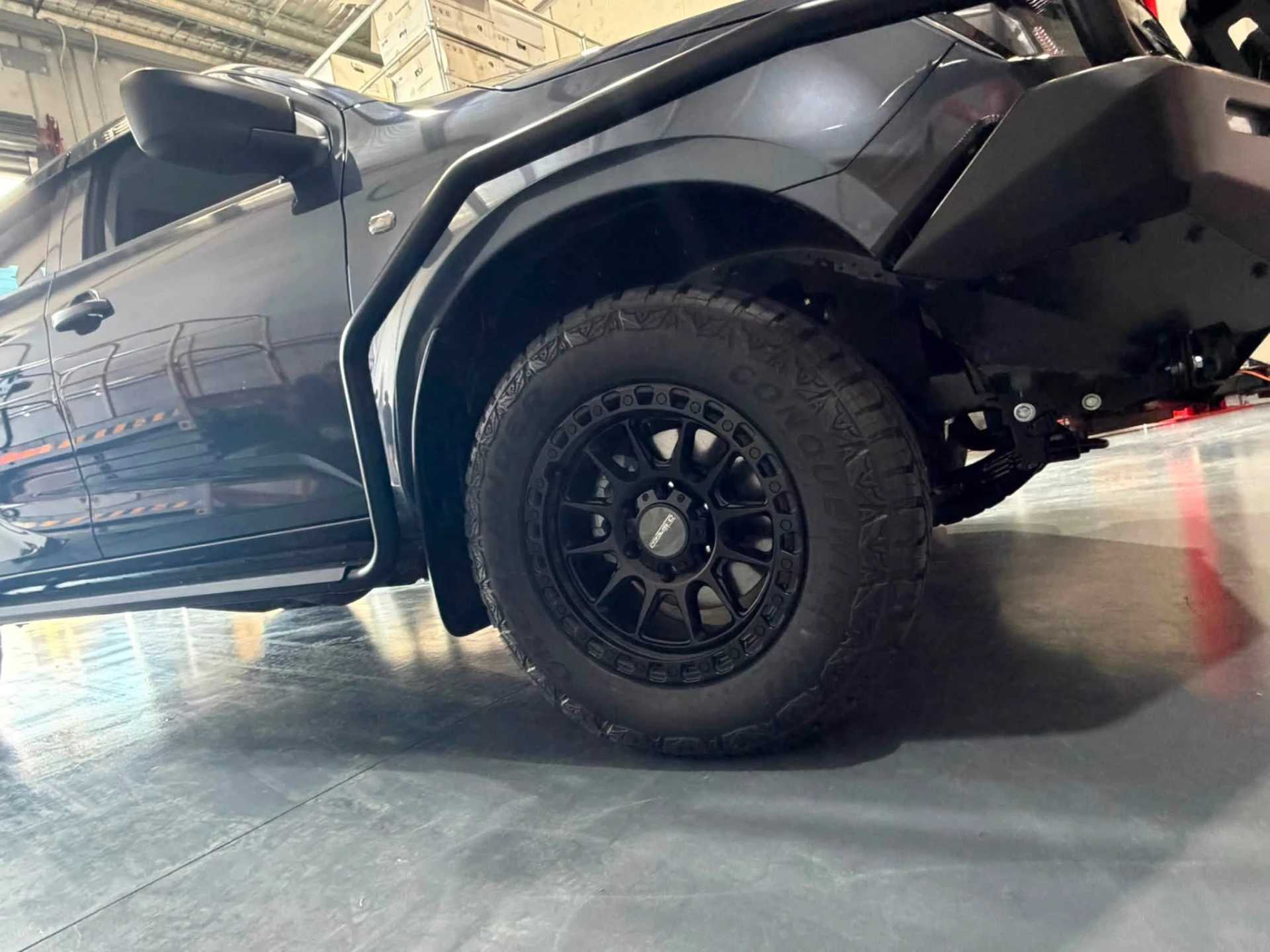 Grey dual cab ute fitted with black alloy wheels and Conquewind all-terrain tyres in the fitting bay at Australia's Most Wanted Wheels and Tyres Bathurst in Kelso
