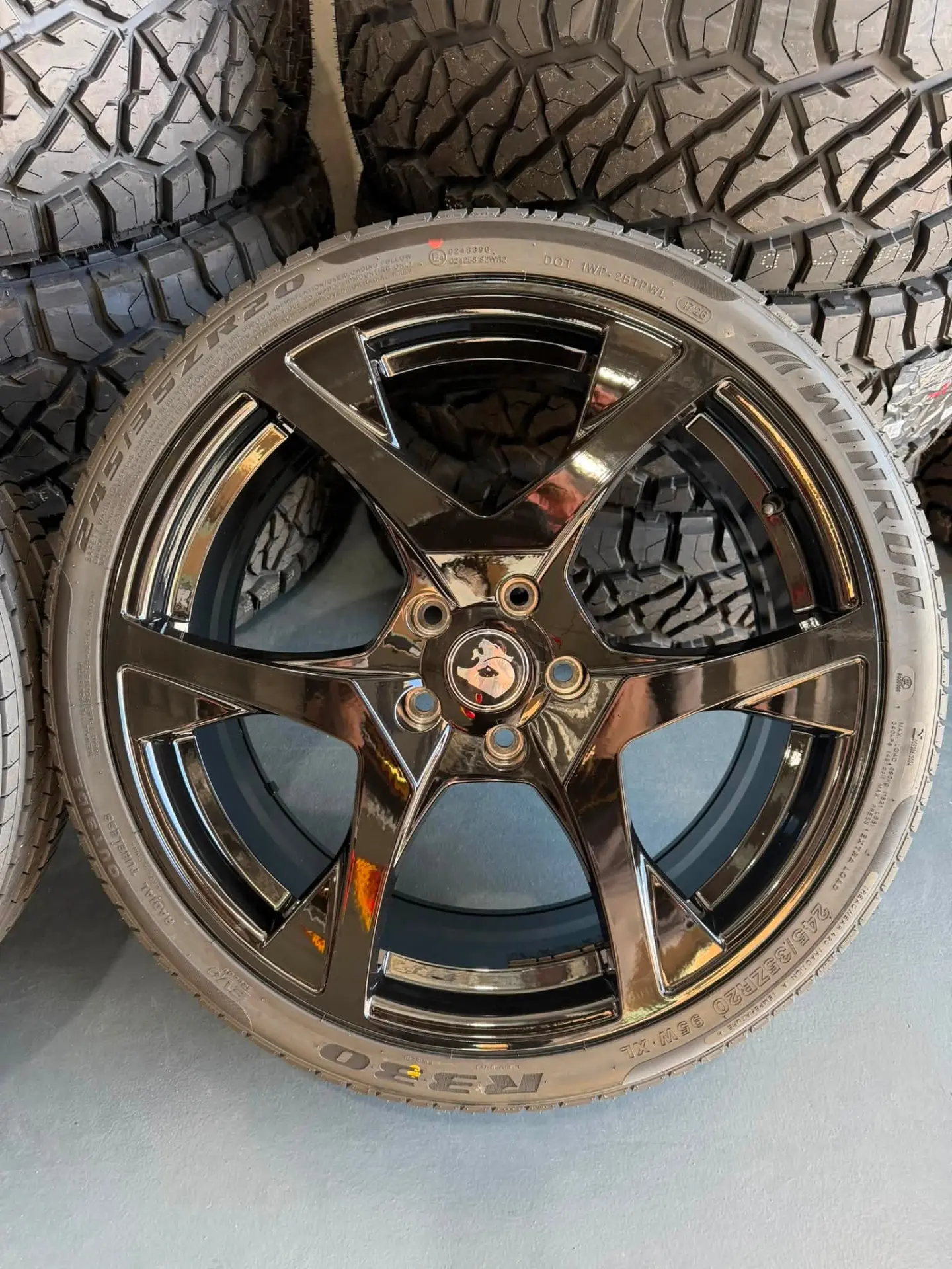 Black chrome five spoke alloy wheel fitted with a Winrun R330 tyre in front of stacked 4WD tyres at Australia's Most Wanted Wheels and Tyres Bathurst in Kelso